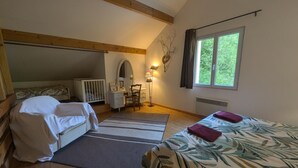 Een slaapkamer met een stapelbed, een bureau met stoel, een kaptafel met spiegel, een lamp en een raam met uitzicht op groen.