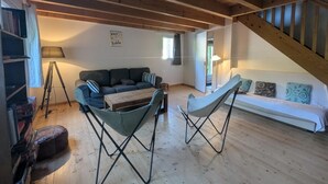 Een kamer in loftstijl met een houten plafond, een bank, een kleine tafel en een stoel.