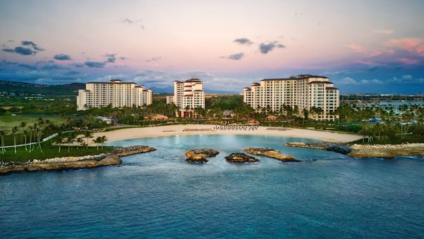 A coastal resort with multiple high-rise buildings, a sandy beach, and a calm sea. - Amazing Private Beach Resort on West Side of Oahu (Kapolei)