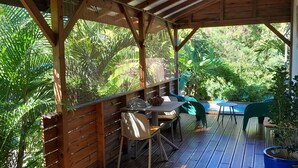 Eine Terrasse im Freien mit Holzmöbeln, einem Pool und üppiger Bepflanzung.