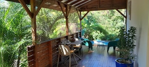 Eine Terrasse im Freien mit Holzmöbeln, einem Pool und üppiger Bepflanzung.
