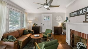Ein Wohnzimmer mit einer Couch, Sesseln, einem Kamin und einem Deckenventilator.