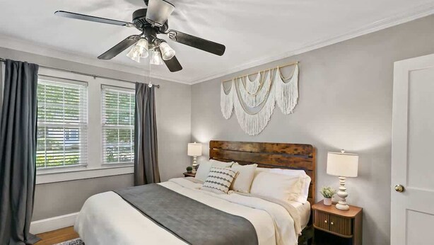Ein Schlafzimmer mit Bett, Deckenventilator, Nachttisch und einer Wanddekoration aus Makramee.