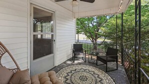 Eine überdachte Veranda mit Deckenventilator, einem gemusterten Teppich und Gartenmöbeln.