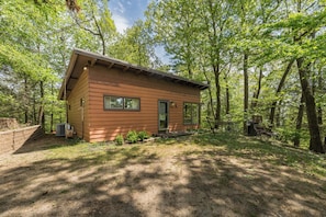 A small cabin with a front porch, surrounded by trees.