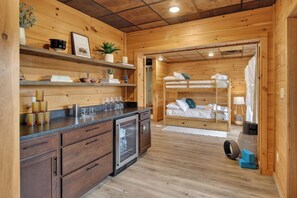 Interior de uma cabana de madeira com cozinha, beliche e pequeno armário.