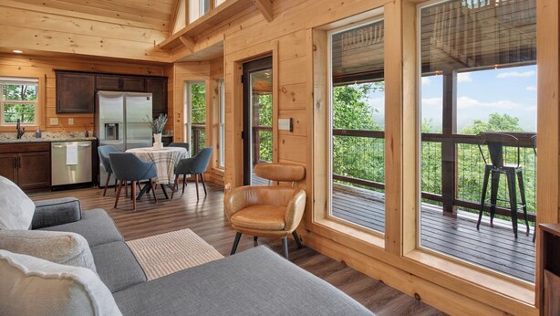 L’intérieur d’un chalet en bois comprend une cuisine, un coin repas et de grandes fenêtres.