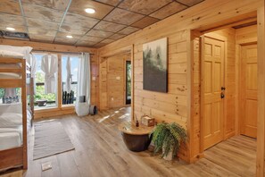Een houten blokhut met een stapelbed, een ronde tafel met een plant erop en een schilderij aan de muur.