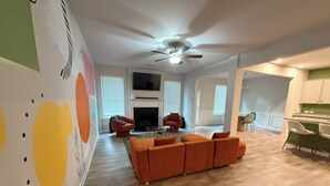 Een moderne woonkamer met een open haard, een oranje bank en een plafondventilator.