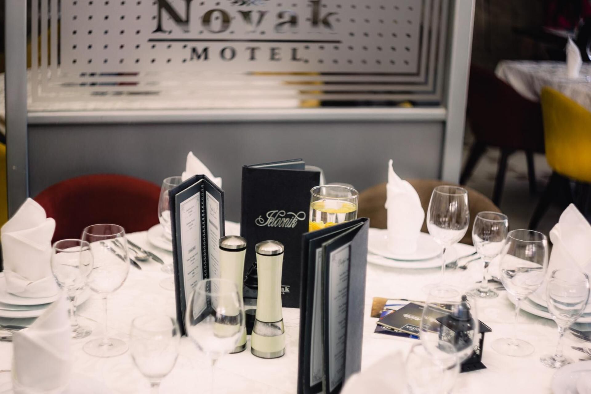Tavola imbandita per la cena, con un espositore per il menu, bicchieri e un candelabro.