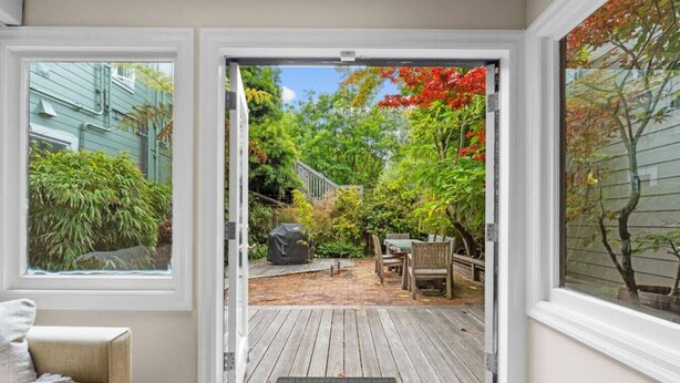 A wooden deck with a covered table and chairs, a covered grill, and a small garden area with various plants and trees. - SF Presidio Heights Haven + Steps 2 Presidio Park (San Francisco)