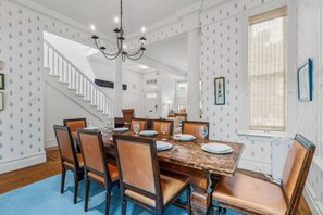 A dining room with a large table set for six, surrounded by chairs, a chandelier, and a staircase leading to another level. - SF Presidio Heights Haven + Steps 2 Presidio Park (San Francisco)
