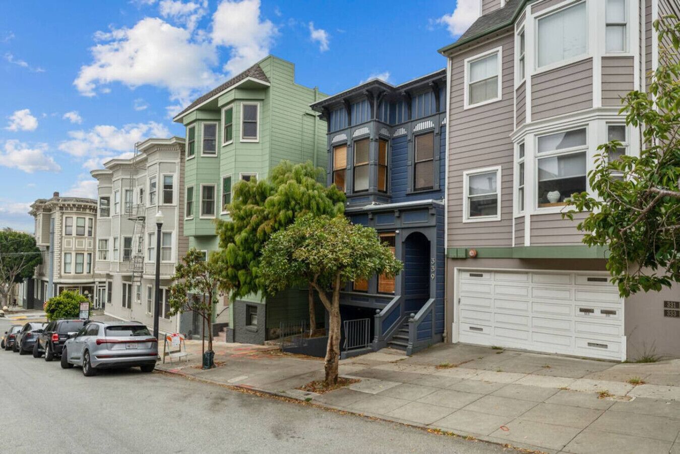 A row of multi-story residential buildings with a tree in the foreground.
