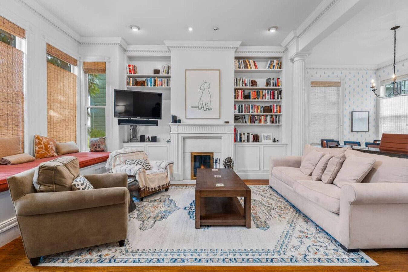 Een woonkamer met een open haard, boekenkasten, een televisie en zitplaatsen.