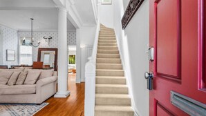 A staircase leading to a landing, a red door, and a living room with a beige sofa. - SF Presidio Heights Haven + Steps 2 Presidio Park (San Francisco)