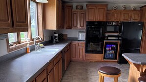 A kitchen with wooden cabinets, a built-in oven, microwave, refrigerator, and a beverage dispenser.