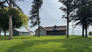 A grassy field with a large building and a barn in the background.