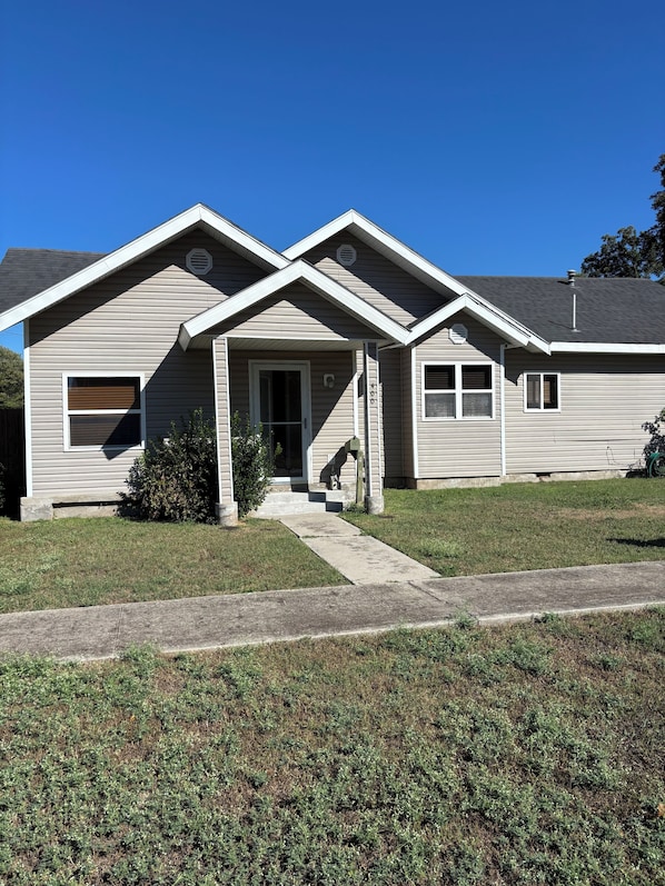 A two-story house with a front porch, a garage door, and a small front yard.