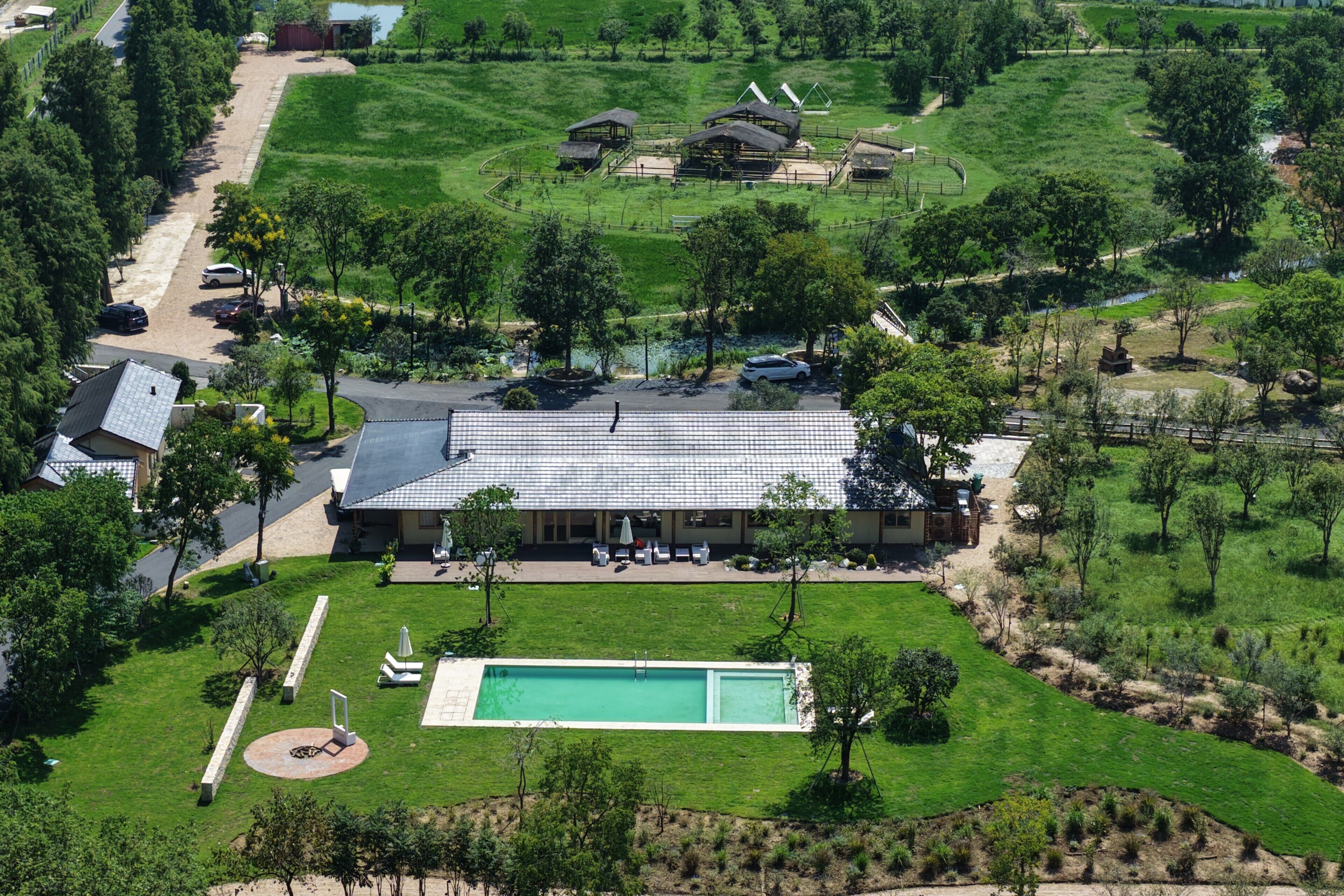Una casa espaiosa amb piscina, envoltada d'un jardí ben cuidat i arbres.