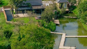 Una casa moderna con un amplio patio, un pequeño muelle para botes y un estanque.