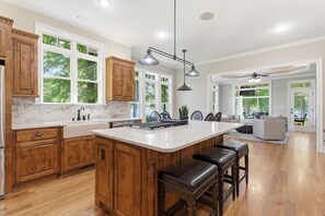 Een ruime keuken met houten kastjes, een groot eiland en een eethoek met uitzicht op de omgeving.