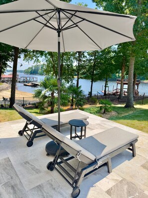 A sun lounger with a canopy, a small table, and a view of a lake and dock. - Entertainers Dream! Private Pool, Spa, Pool Table, Shuffleboard, Arcade, Firepit, Tiki Bar! (Terrell)