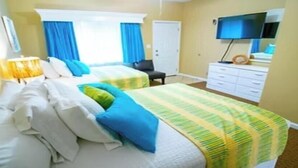 A hotel room with two beds, a desk, a chair, a TV, and a dresser.