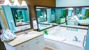 A bathroom with a sink, mirror, bathtub, and a towel rack.