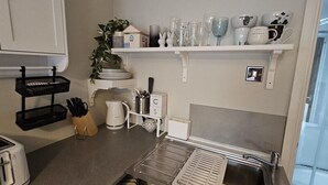 Uma cozinha compacta equipada com torradeira, chaleira e pia.
