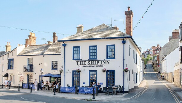A traditional building with a sign reading 'The Ship Inn' and a street in front.