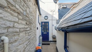 Une ruelle étroite, située entre deux immeubles, avec une porte bleue et une antenne parabolique sur le côté gauche.