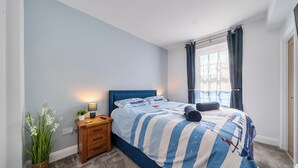 Une chambre à coucher avec un lit, une table de chevet, une lampe et une plante en pot.