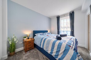 A bedroom with a bed, bedside table, lamp, and a potted plant. - 4 Bed - Sleeps 8 - Pool Table -Sea View - Parking (Swanage)
