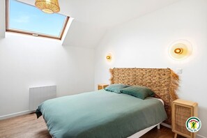 Ein Schlafzimmer mit Bett, Fenster, Deckenventilator und Heizkörper.