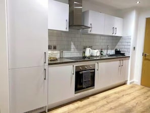 A modern kitchen with white cabinets, a stainless steel oven, and a tiled backsplash.