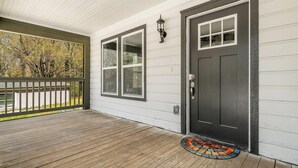 A covered porch with a dark door, large windows, and a wooden deck. - New Renovated 3BD-2BA Home • Minutes to Mercedes Benz, Midtown and Beltline (Atlanta)