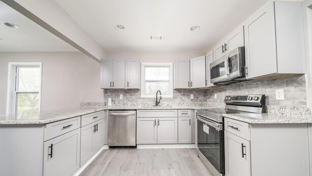 A modern kitchen with white cabinets, granite countertops, a stainless steel dishwasher, a built-in microwave, and a stainless steel oven. - New Renovated 3BD-2BA Home • Minutes to Mercedes Benz, Midtown and Beltline (Atlanta)