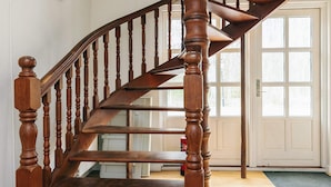 Una escalera de madera con barandilla que conduce a una puerta con ventanas.