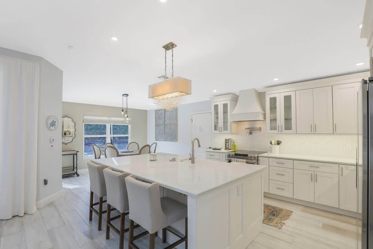 A modern kitchen with a large island, white cabinetry, and pendant lighting.