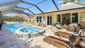 A covered outdoor area with a swimming pool, lounge chairs, and a patio with outdoor furniture. - 3BR 3BA House - Pool & Spa - Beach Access Included (Marco Island)