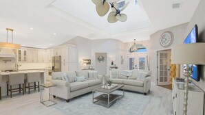 A spacious living area with a sofa set, a coffee table, and a dining area with bar stools. - 3BR 3BA House - Pool & Spa - Beach Access Included (Marco Island)