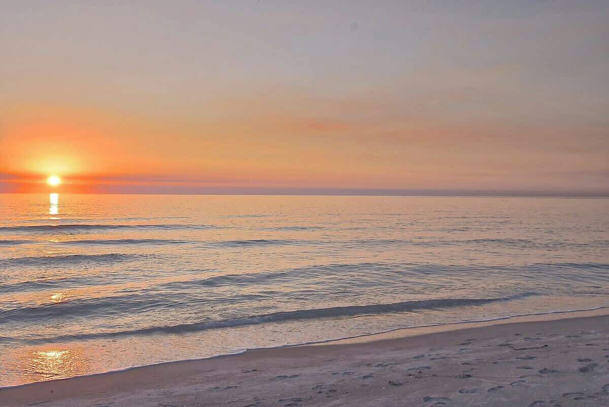 A beach with a sunset over the water.