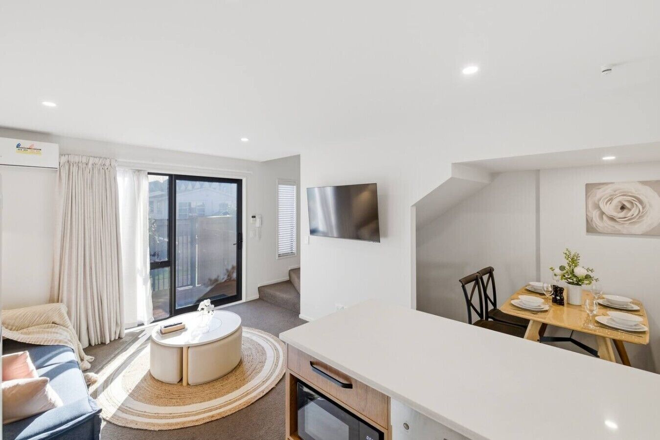 Una habitación de hotel moderna con balcón, zona de comedor y un televisor de pantalla plana grande.