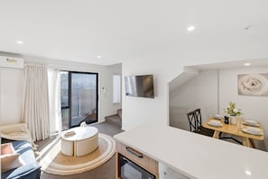 Ein modernes Hotelzimmer mit Balkon, einer Essecke und einem großen Flachbildfernseher.