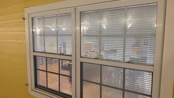 A window with blinds, a yellow wall, and a visible brick wall outside.