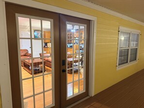 Ein Flur mit einer braunen Tür, die in ein Wohnzimmer führt, mit einem braunen Ledersofa, einem Holztisch und einem Esstisch mit Stühlen.