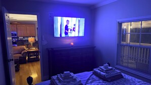 Ein Schlafzimmer mit einem Bett, einem Fernseher, einem Schminktisch und einem Fenster.