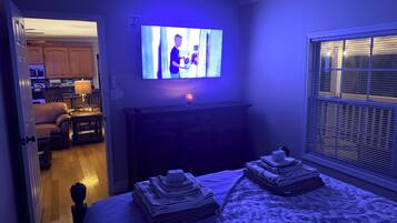 A bedroom with a bed, a TV, a dresser, and a window.