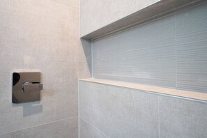 A bathroom with a tiled wall, a shower enclosure, and a built-in towel rack. - Modern DC Stay Steps to Convention Center (Washington)