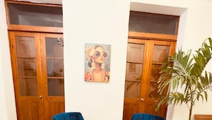 Una habitación con dos sillas azules, una planta en maceta y un cuadro en la pared.